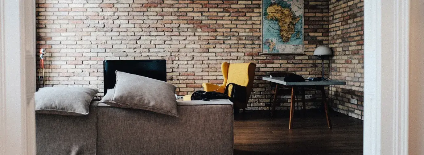 living room with brick walls, a grey couch and a cartographer's map of Africa on the wall