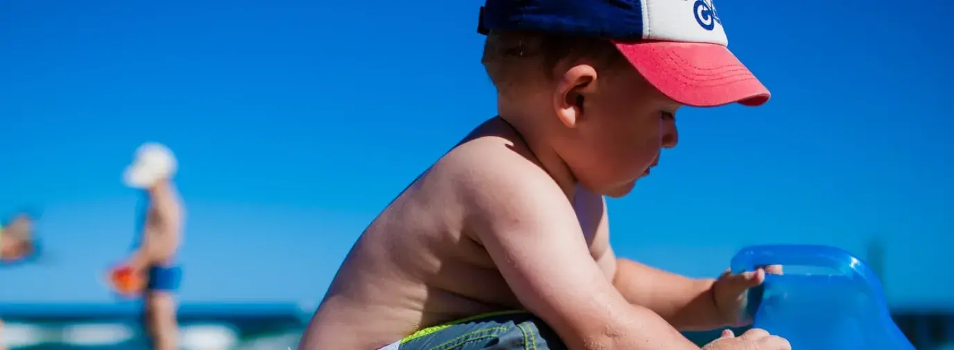Image: child playing with toys in the sand. Title: Green Your Holidays: Avoiding Toxic Toys