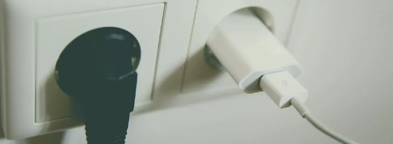 Image: two electrical outlets with electronics plugged in. Title: More Steps to Energy Efficiency