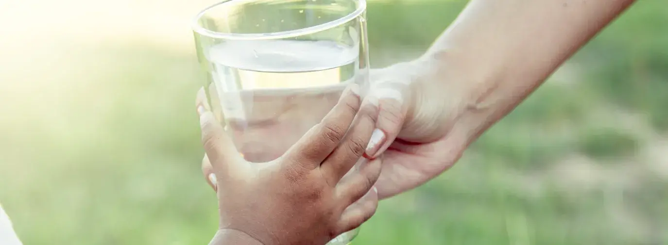 Image: adult handing glass of water to a child. Title: Bottled Water vs. Tap: Which is Best?