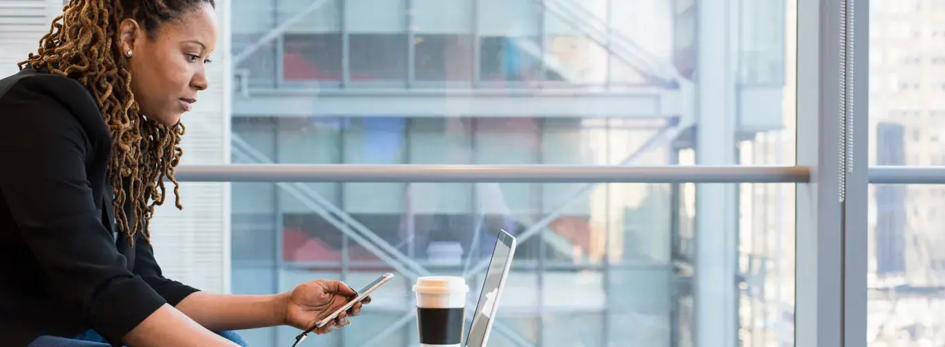 Image: person working on laptop and smartphone. Topic: Green Business