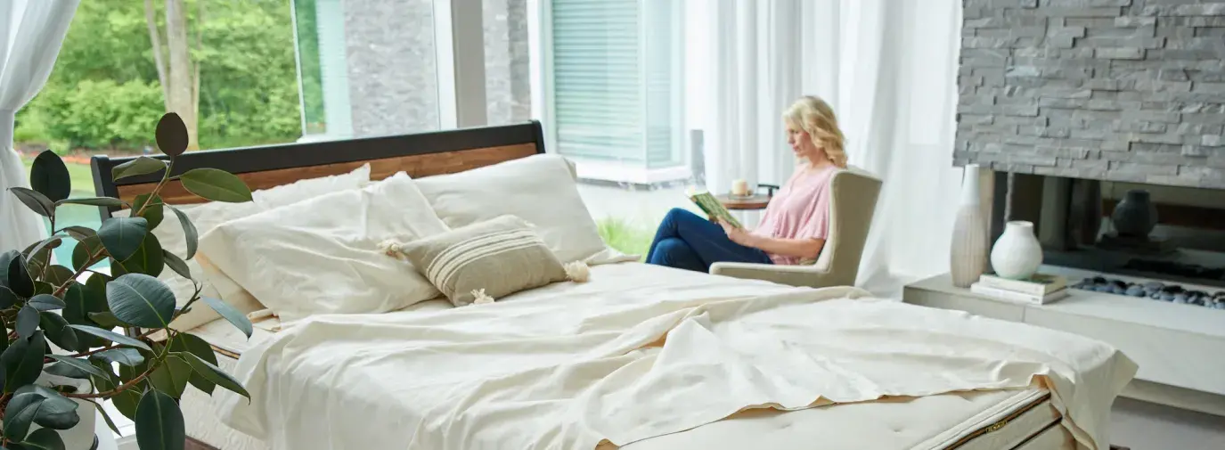 woman reading next to a bed