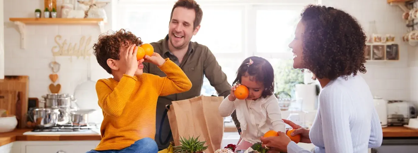 family laughing around a counter with groceries on it