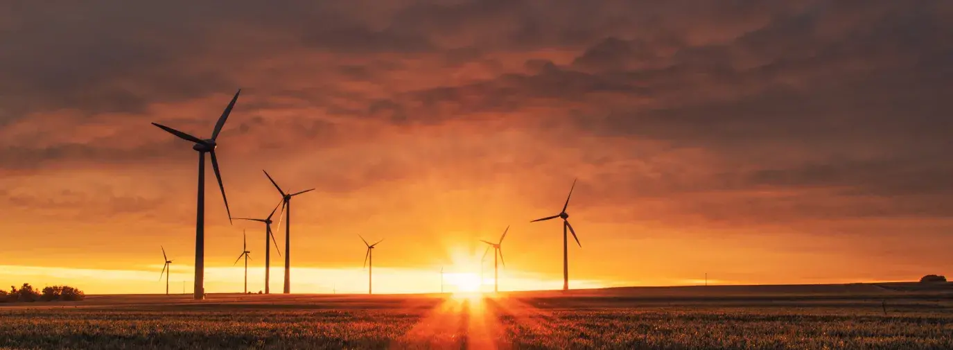 Image: wind turbines in a field against the setting sun. Title: Is Verizon’s Green Bond Tipping the Scales on Clean Energy?