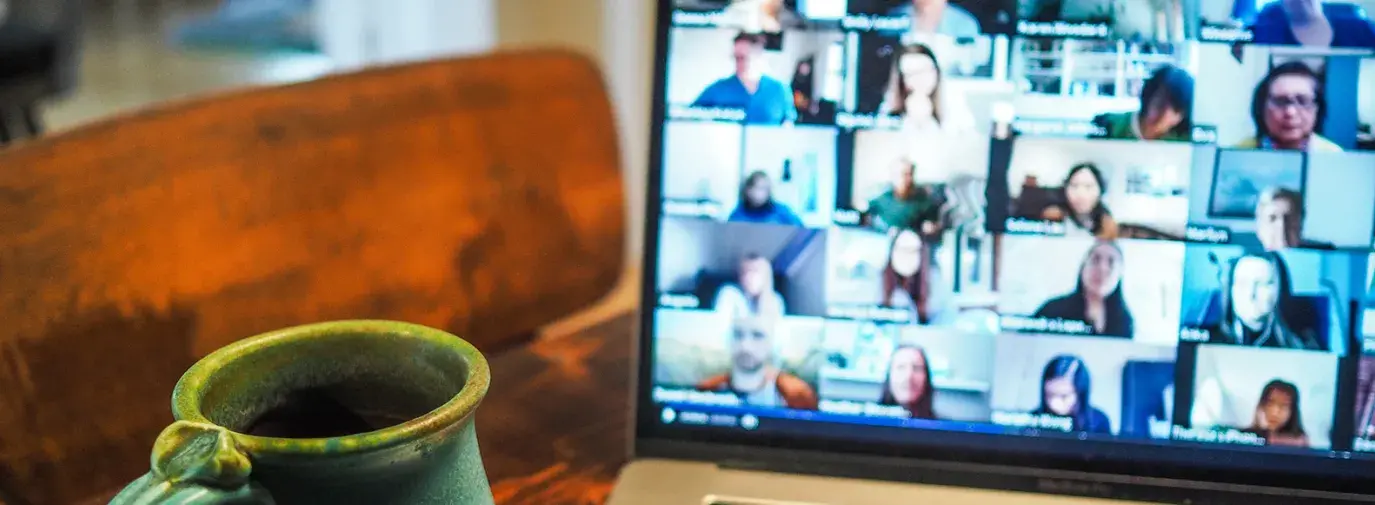 zoom video open on a laptop with a mug next to it