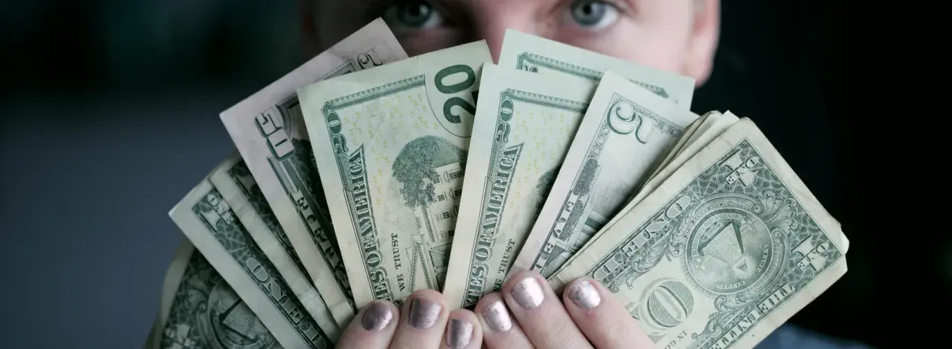 Image: person holding American currency. Title: Divest & Reinvest 