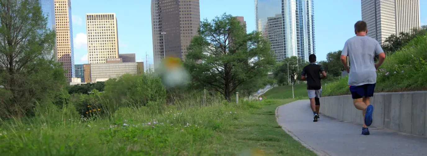Two people running in a green space at Buffalo Baou Park in Houston, Texas.