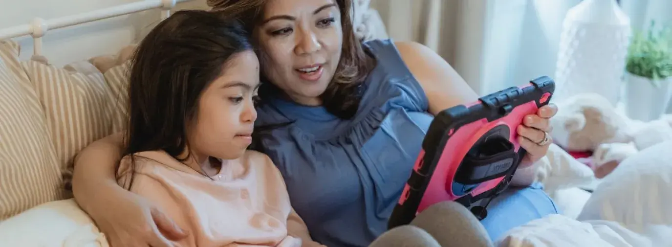 mother and daughter looking at a tablet together and talking