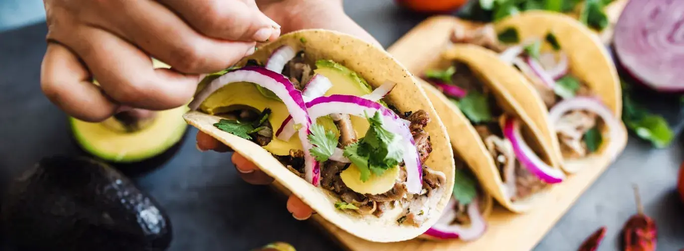 A taco filled with mushrooms, avocado, red onion, and cilantro. 