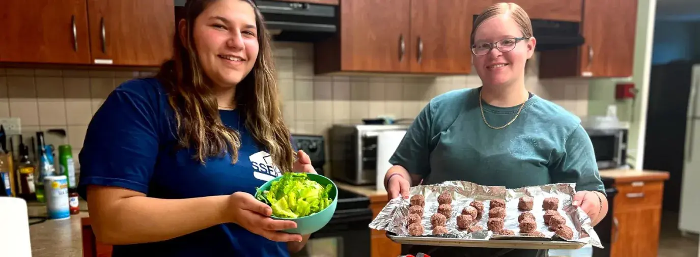 two college students showing what they're making for dinner. Baking meatballs and salad prepping.