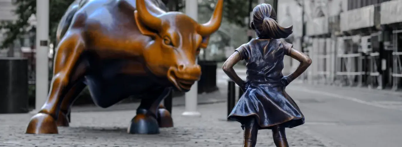 photo of the wall street bull facing a brass statue of a young girl standing proudly with her hands on her hips.