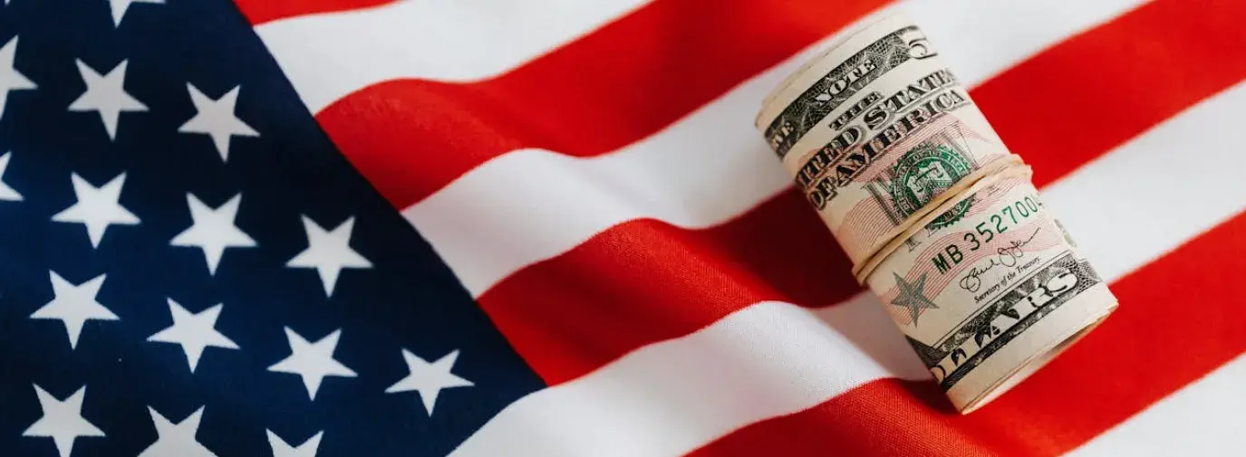 a roll of five US dollars on top of the US flag.