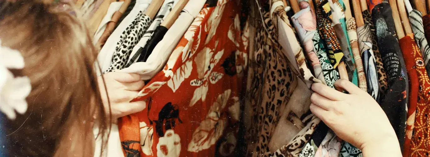 A woman browsing colorful clothes hanging on a rack. 
