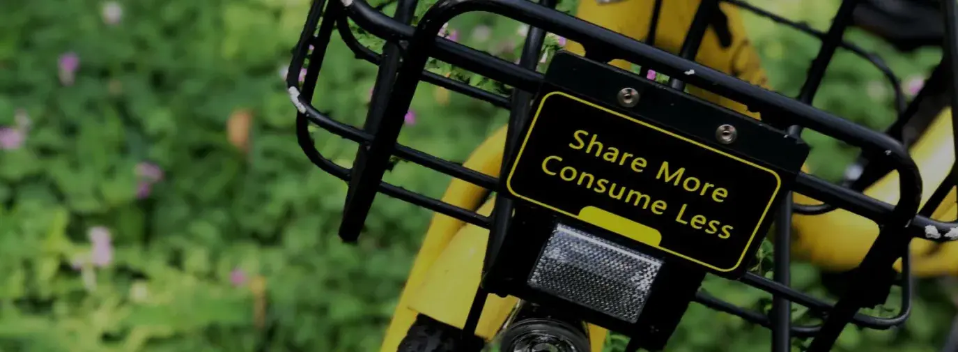 a yellow bike with a basket that reads "share more, consume less"