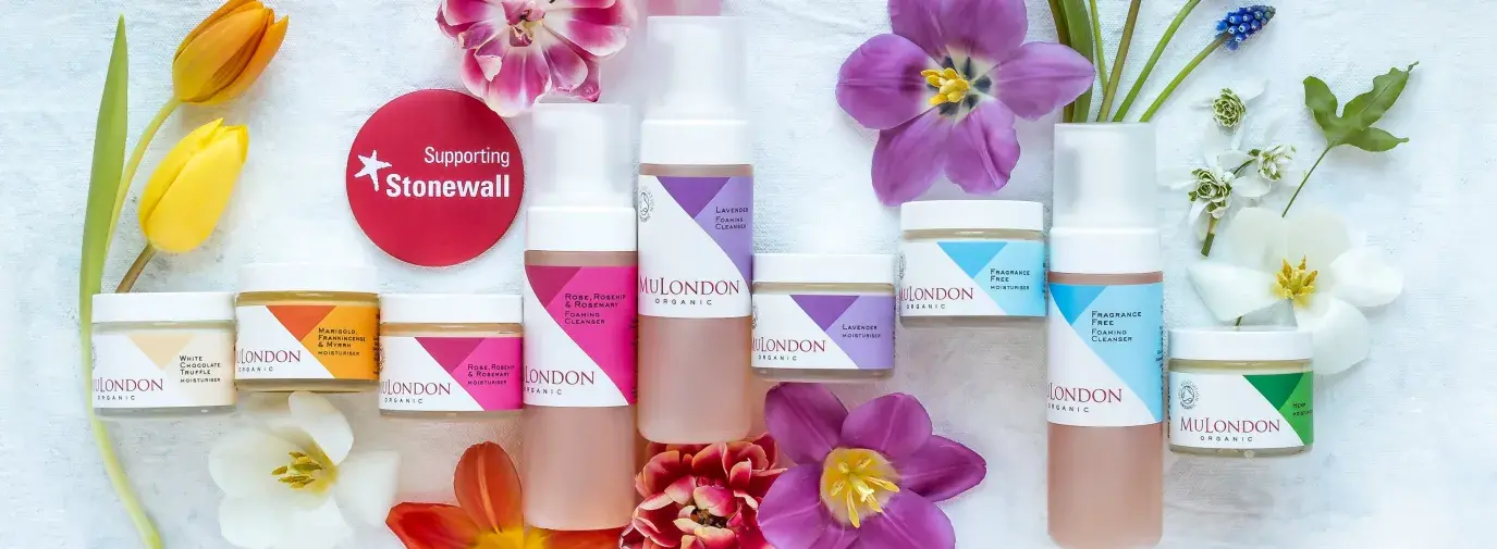 A line of colorful skincare products in bottles surrounded by colorful flowers