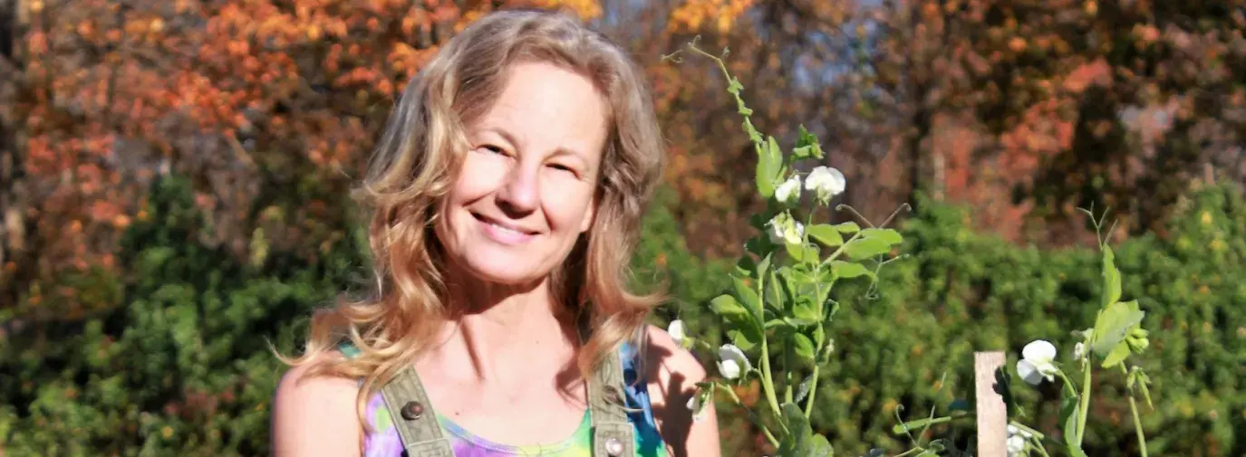 Lisa standing buy a trellised bean plant on an autumn day