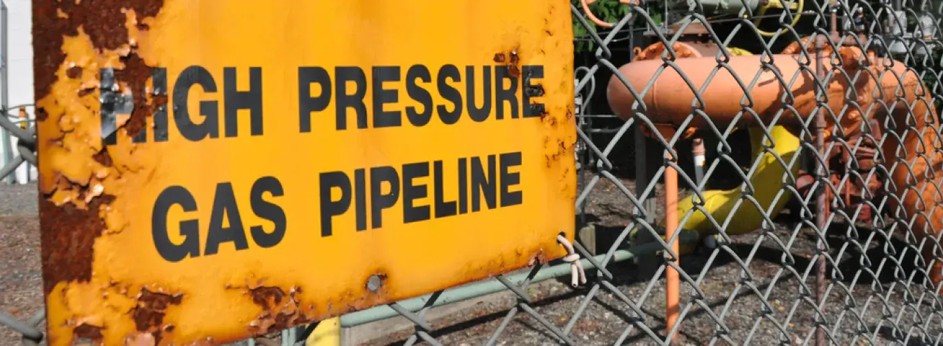 Image yellow sign reading "Caution: High Pressure Gas Pipeline." Topic: Natural Gas Pipeline and Infrastructure Explosions Nationwide