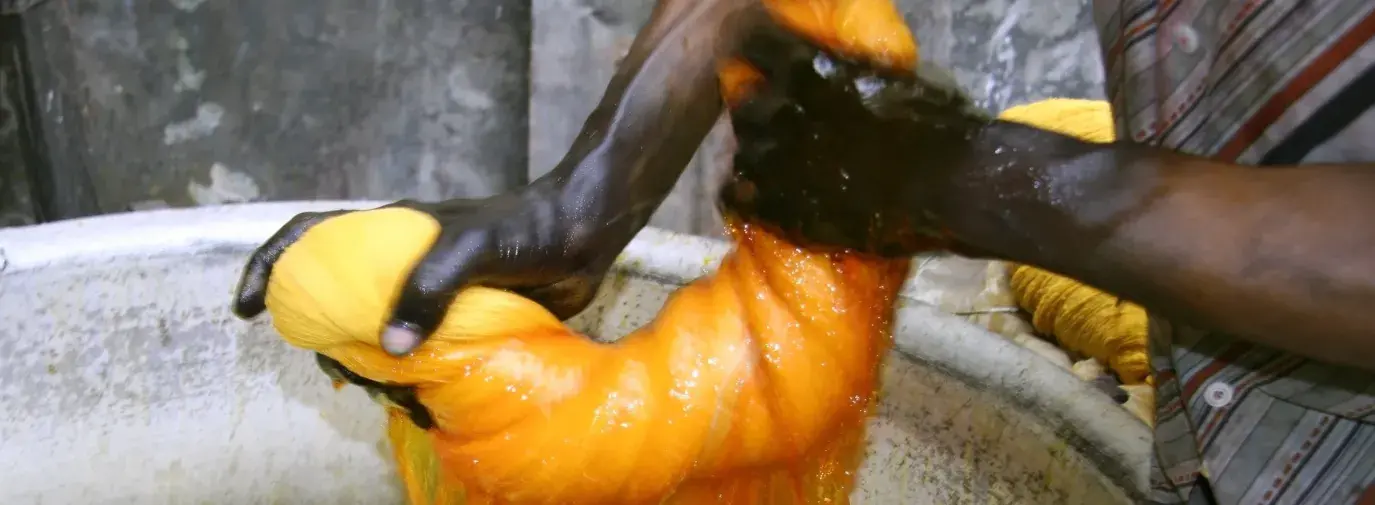 Image: person wringing out dyed fabric. Topic: Toxic Textiles Report