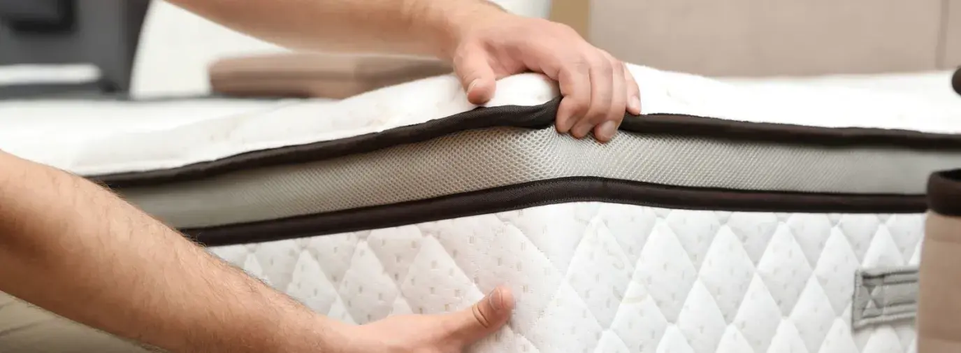 two hands lifting and placing a mattress on a bedframe