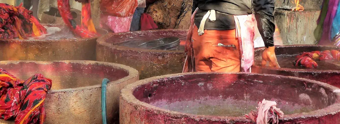 Image: workers dyeing textiles in large concrete vats. Topic: Toxic Textiles
