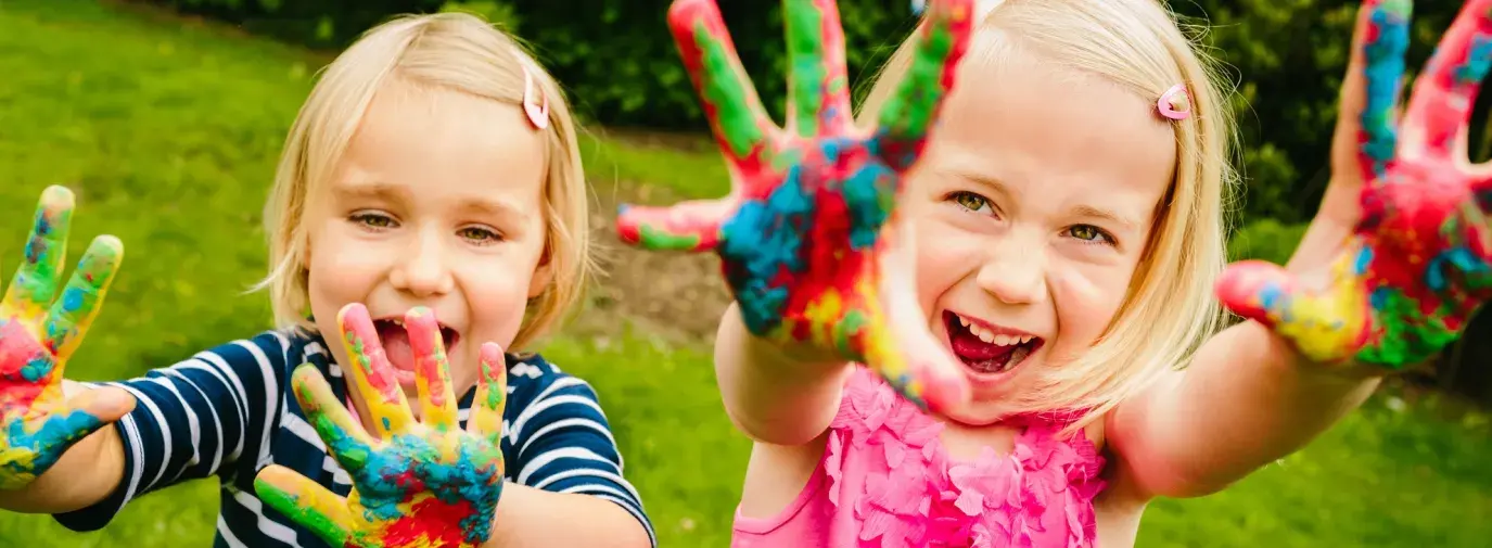 Image: kids playing, with paint on their hands. Title: Green Kids