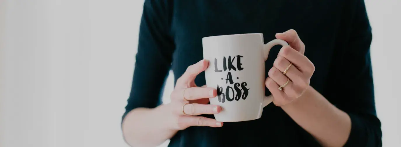 woman in black shirt holding white mug that reads Like A Boss