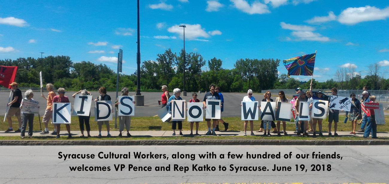 A group of Syracuse Cultural Workers and protesters holding signs with individual letters reading: "Kids not walls."