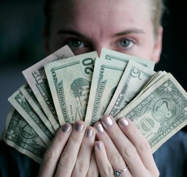 Image: person holding American currency. Title: Divest & Reinvest 
