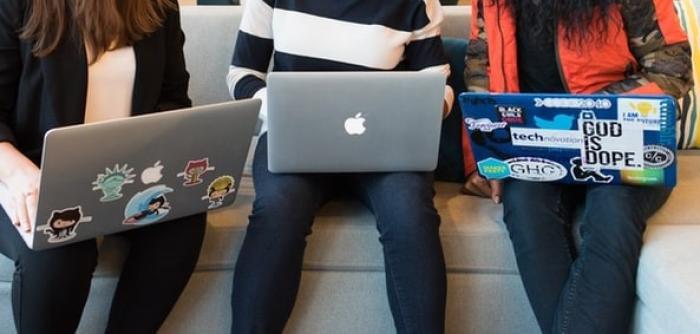 three women sit together with laptops 