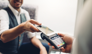 Image: shopper using contactless payment at a cashier. Title: Survey: Millennials Drive Demand for Digital Receipts