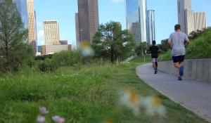 Two people running in a green space at Buffalo Baou Park in Houston, Texas.