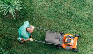man pushing an orange lawnmower