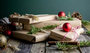 Gifts wrapped in brown paper with pine and ornaments around them. Sustainable gifts holidays.