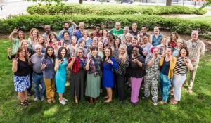 three rows of green america staff making the hand sign for I Love You in ASL