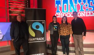 speakers at a Tony's Chocolate event standing next to a fair trade banner.