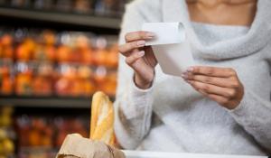 Image: shopper in a grocery store holding a receipt. Title: What do People Think of Paper Receipts?